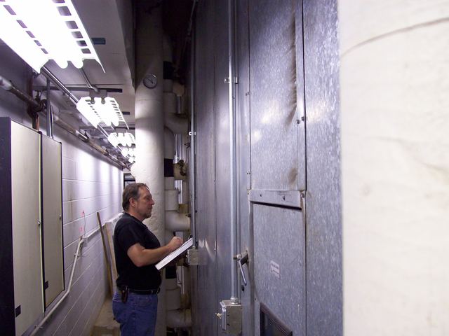 Mark F Gremillion reading air handler information in a mechanical room